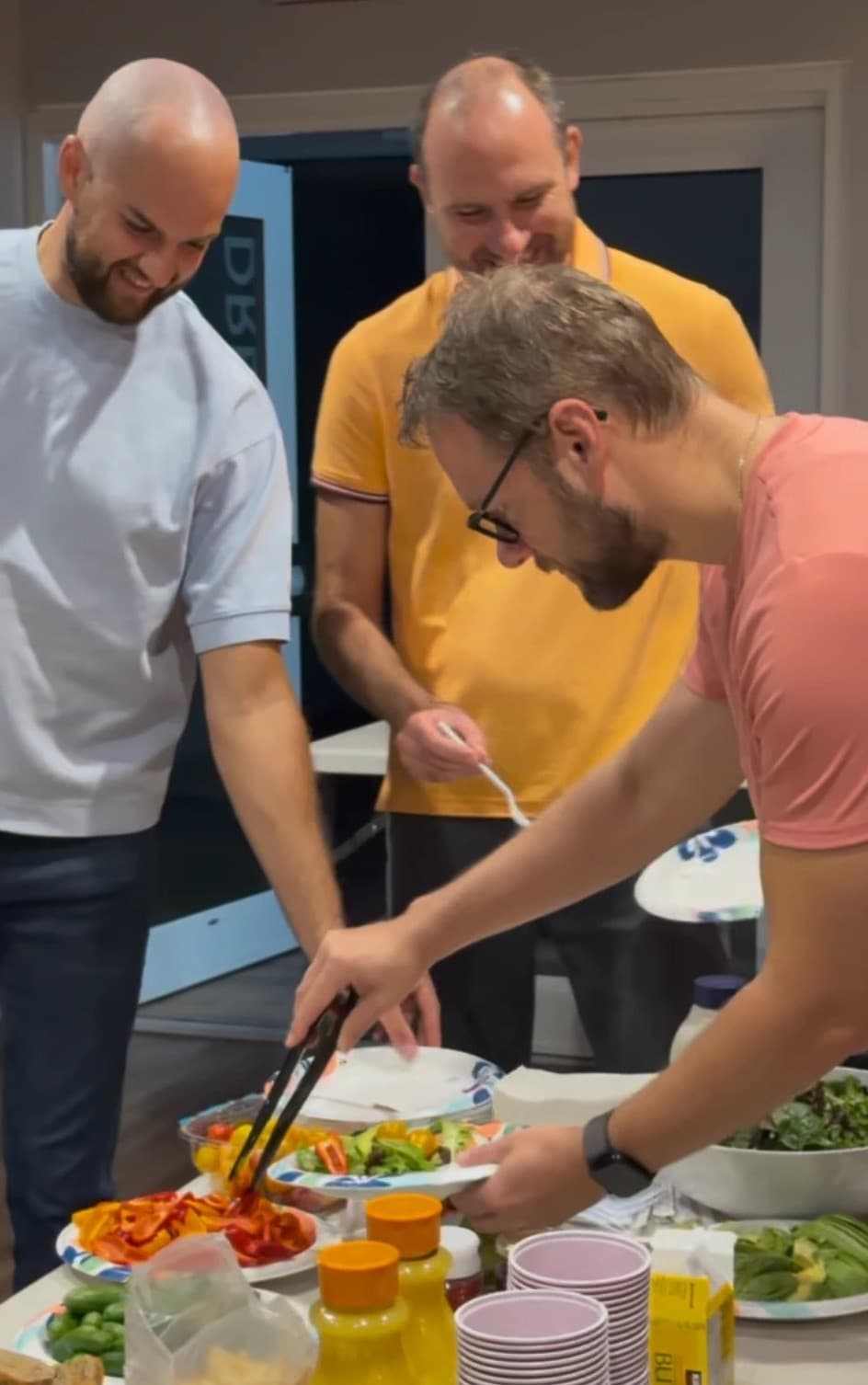 Men filling their plates with fresh vegetables at the breakfast table