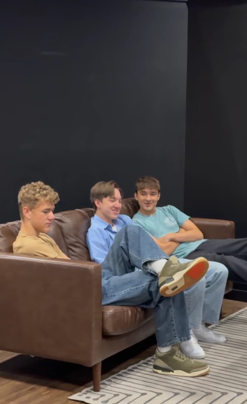 Three young men listening on a sofa